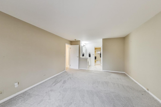 spare room with baseboards and light carpet