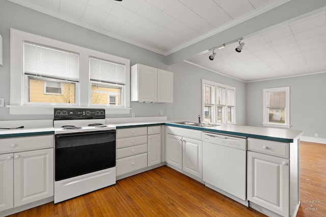 kitchen featuring white dishwasher, electric range oven, ornamental molding, a sink, and a peninsula