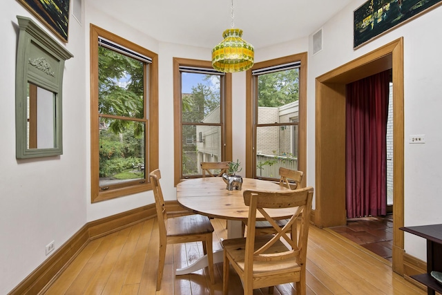 dining space featuring light wood-style floors, a notable chandelier, baseboards, and visible vents