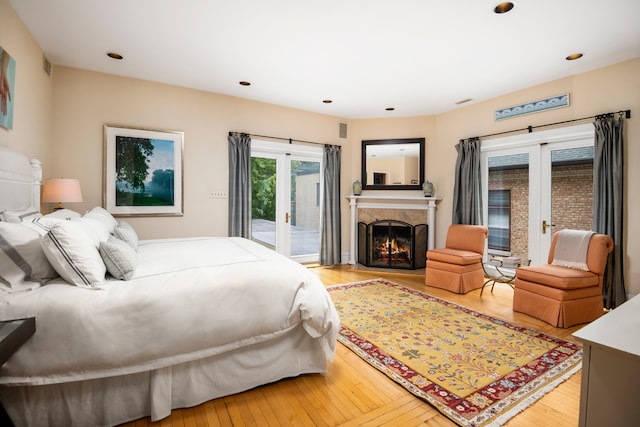 bedroom featuring recessed lighting, access to exterior, light wood-type flooring, and a high end fireplace