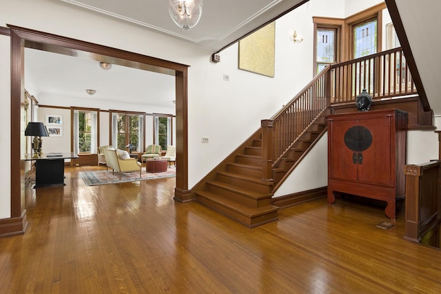 stairs featuring crown molding, baseboards, hardwood / wood-style floors, and a high ceiling