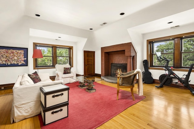 living room with visible vents, baseboards, light wood-style floors, and a fireplace