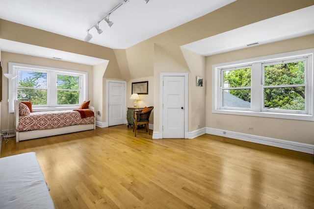 unfurnished bedroom featuring light wood-type flooring, multiple windows, and baseboards
