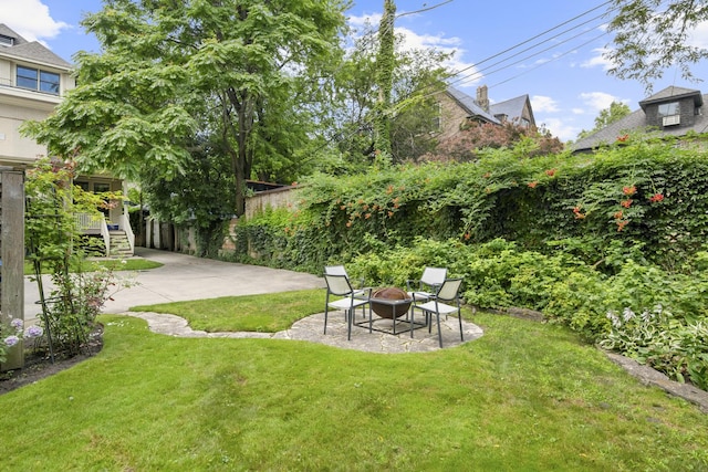 view of yard featuring a patio, a fire pit, fence, and stairs