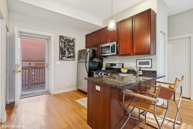 1019 N Washtenaw Ave Unit 2, Chicago, IL 60622 - kitchen with appliances with stainless steel finishes, a sink, a peninsula, light wood-style floors, and a breakfast bar area