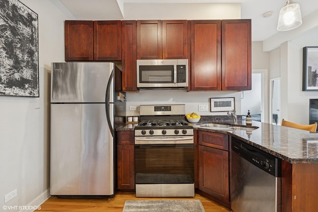 1019 N Washtenaw Ave Unit 2, Chicago, IL 60622 - kitchen with appliances with stainless steel finishes, a sink, dark stone counters, a peninsula, and light wood-style flooring