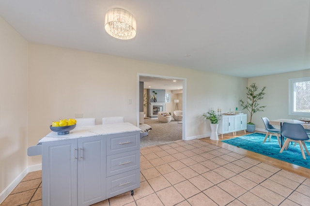 16112 Turner Ave, Markham, IL 60428 - kitchen with light tile patterned floors, baseboards, a chandelier, a glass covered fireplace, and light stone counters