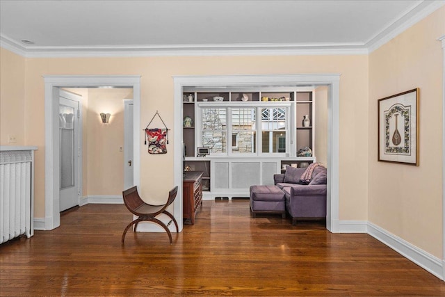 living area with baseboards, wood finished floors, and crown molding