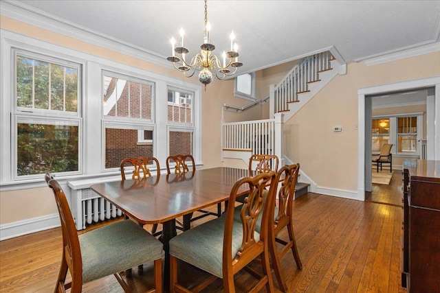 dining space with a chandelier, hardwood / wood-style floors, crown molding, and stairs