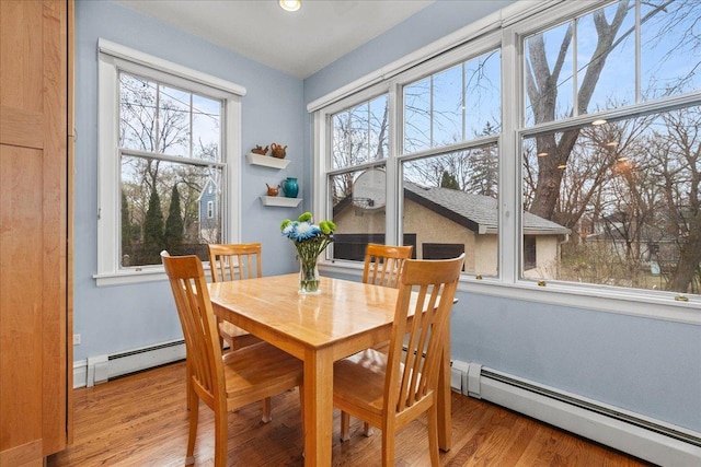 dining area with a baseboard radiator, light wood-type flooring, and plenty of natural light