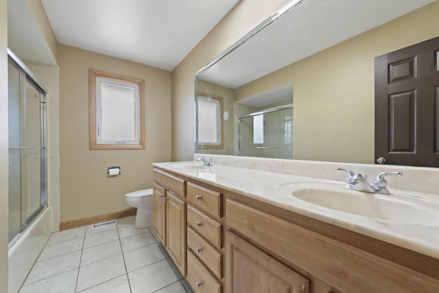 full bathroom featuring toilet, double vanity, a sink, and tile patterned flooring