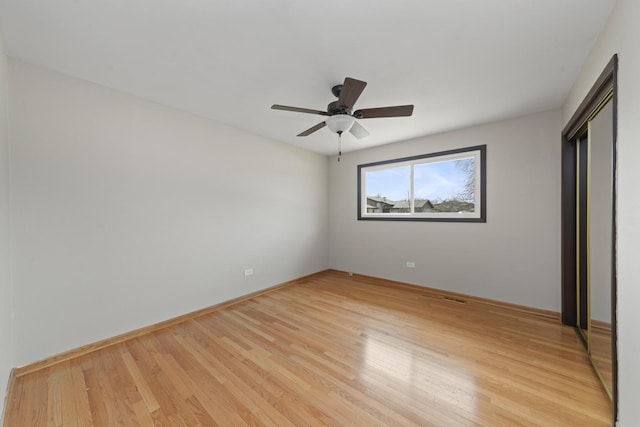 unfurnished bedroom featuring ceiling fan, light wood-type flooring, and baseboards