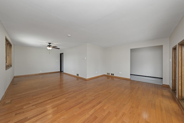 spare room featuring light wood-style floors, visible vents, baseboards, and ceiling fan