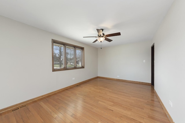 spare room featuring light wood finished floors, ceiling fan, baseboards, and visible vents