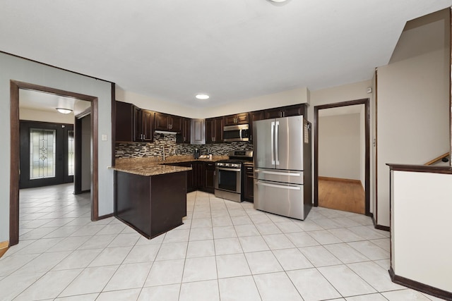 kitchen featuring light tile patterned floors, dark brown cabinetry, light stone counters, stainless steel appliances, and backsplash