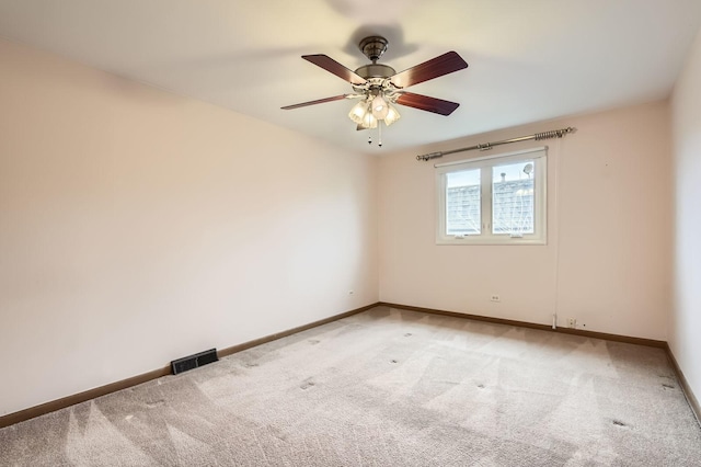 spare room with visible vents, light colored carpet, baseboards, and a ceiling fan