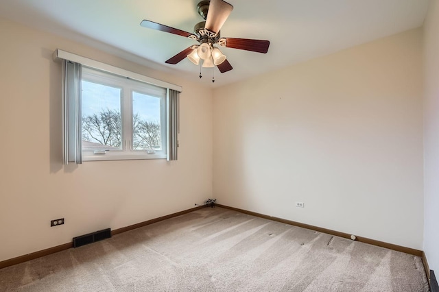 carpeted spare room featuring visible vents, baseboards, and a ceiling fan