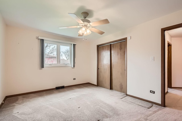 unfurnished bedroom with ceiling fan, a closet, visible vents, light carpet, and baseboards