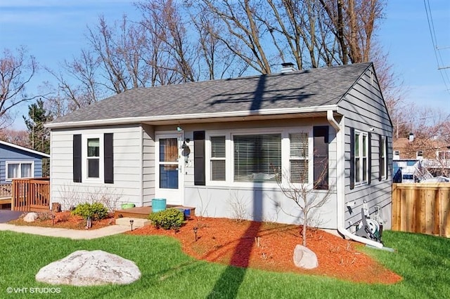 bungalow with roof with shingles, a chimney, fence, and a front lawn