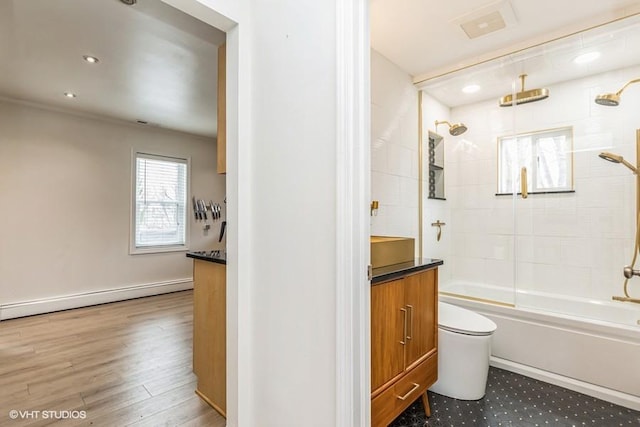 bathroom with visible vents, toilet, baseboard heating, vanity, and a combined bath / shower with rainfall shower