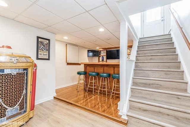 bar with baseboards, recessed lighting, stairway, a dry bar, and wood finished floors