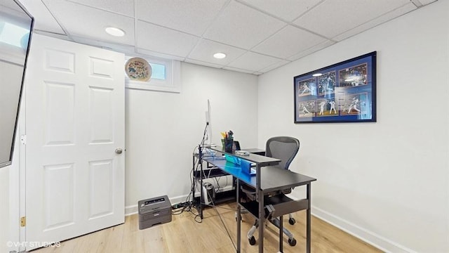 office area featuring light wood-style flooring, baseboards, and a drop ceiling