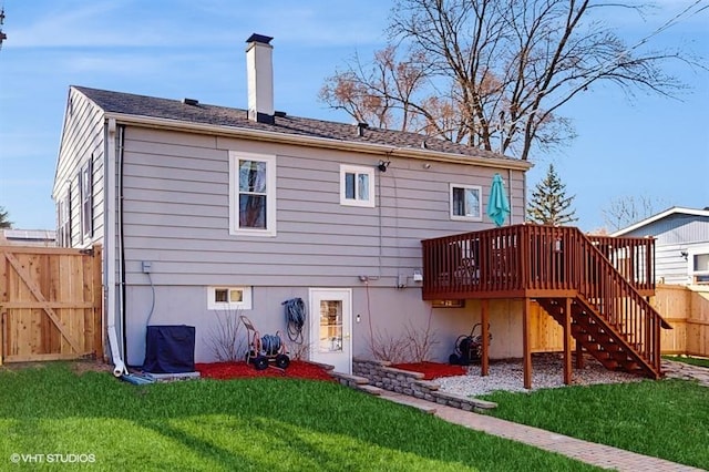 back of house featuring a chimney, stairs, a wooden deck, fence, and a lawn