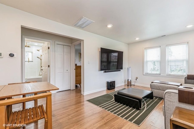 living room featuring recessed lighting, light wood finished floors, visible vents, and baseboards