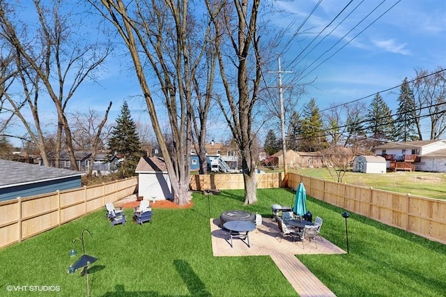 view of yard featuring an outbuilding, a shed, a fenced backyard, an outdoor fire pit, and a patio