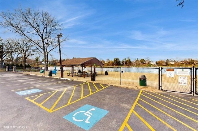 uncovered parking lot with a gazebo, fence, and a gate
