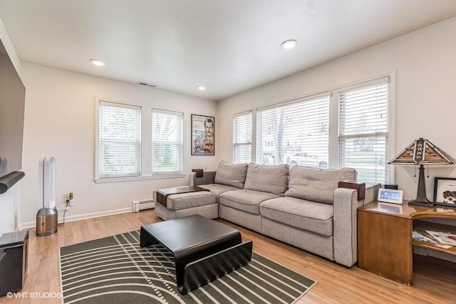 living area featuring a baseboard radiator, wood finished floors, visible vents, and plenty of natural light