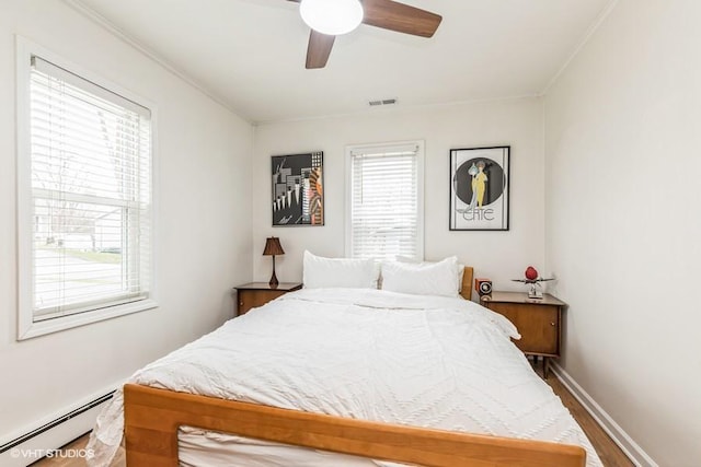 bedroom featuring visible vents, a baseboard radiator, multiple windows, and wood finished floors