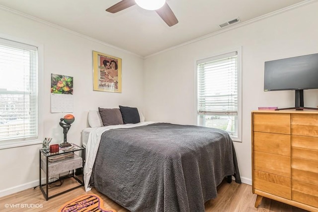 bedroom with baseboards, ornamental molding, a ceiling fan, light wood-style floors, and visible vents