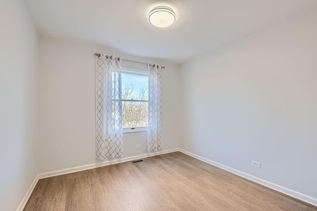 unfurnished room with light wood-style flooring, baseboards, and visible vents