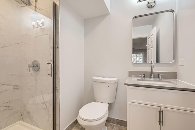 bathroom featuring toilet, a marble finish shower, baseboards, and vanity