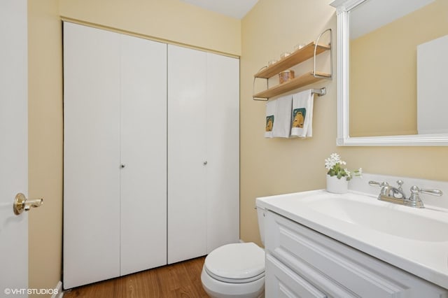 half bathroom featuring wood finished floors, vanity, and toilet