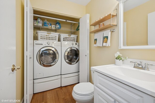 washroom featuring wood finished floors, washer and dryer, laundry area, and a sink