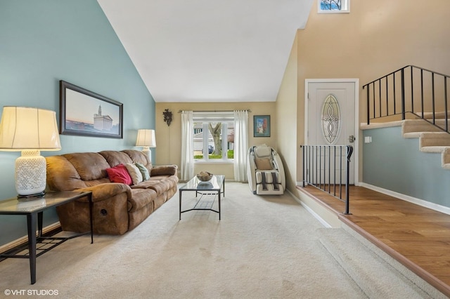 living room with high vaulted ceiling, baseboards, carpet flooring, and stairway