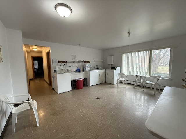 124 N Whistler Ave Unit B8, Freeport, IL 61032 - kitchen featuring light countertops, washer and clothes dryer, white cabinetry, and a baseboard radiator