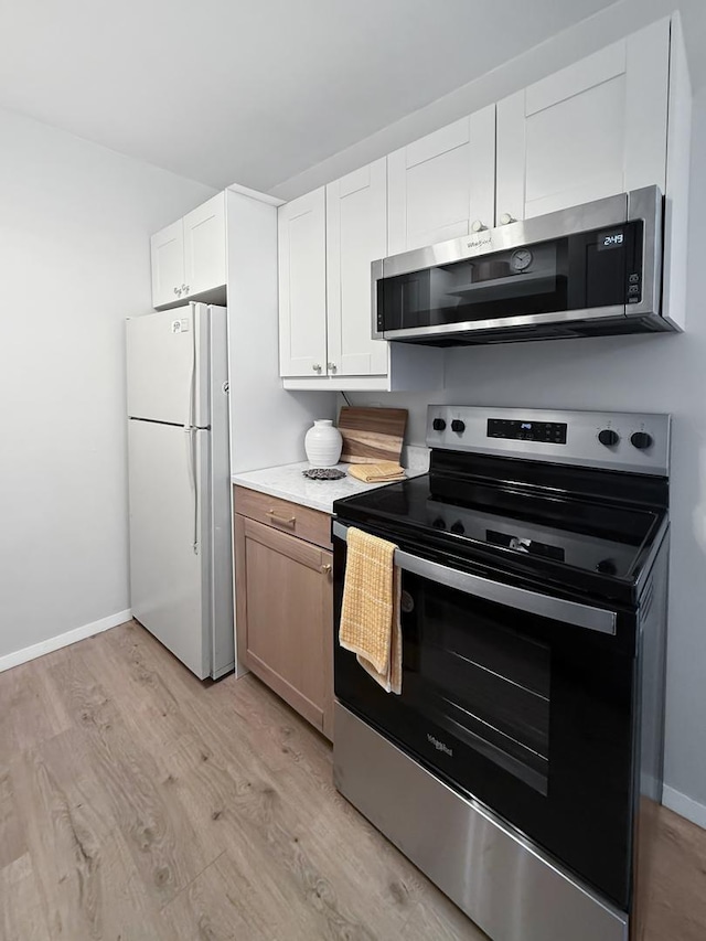 124 N Whistler Ave Unit B8, Freeport, IL 61032 - kitchen featuring white cabinetry, baseboards, appliances with stainless steel finishes, and light wood-style floors
