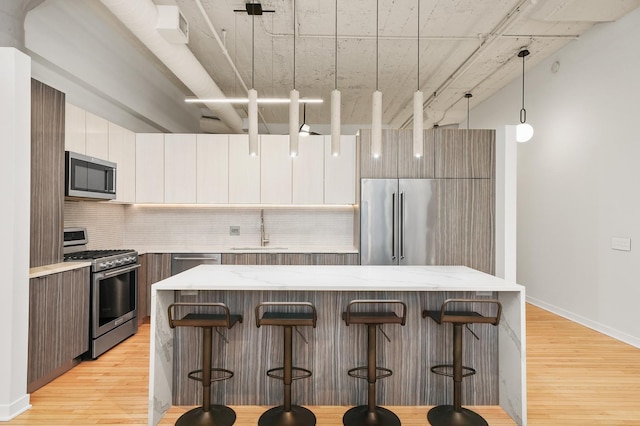 kitchen with light wood-style flooring, modern cabinets, a sink, and appliances with stainless steel finishes