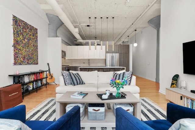 living area featuring rail lighting, light wood-type flooring, and baseboards