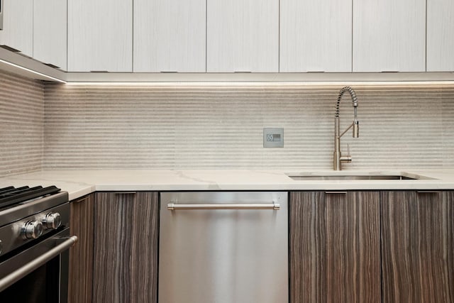 kitchen featuring appliances with stainless steel finishes, a sink, modern cabinets, and dark brown cabinetry