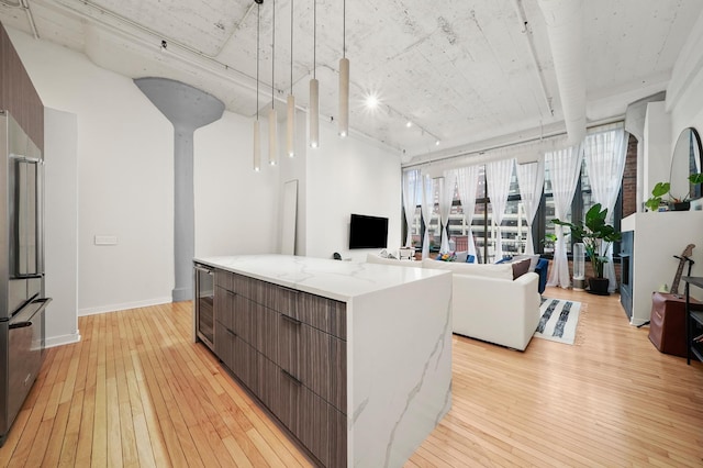 kitchen with light wood-style floors, high quality fridge, modern cabinets, and a kitchen island