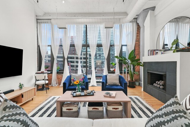 living area with a tiled fireplace, wood finished floors, and a healthy amount of sunlight