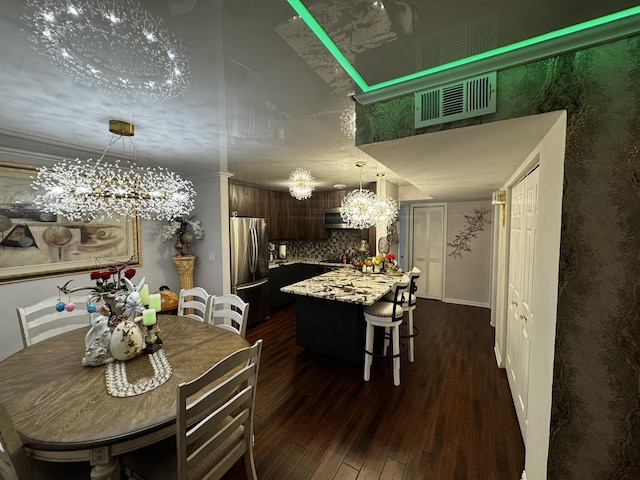 dining room featuring a notable chandelier, a high ceiling, visible vents, and dark wood-style floors