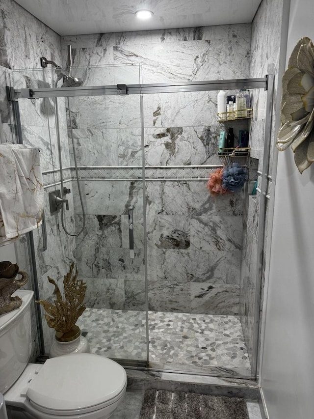 full bath with a marble finish shower and toilet
