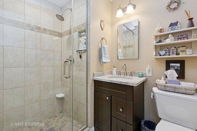 bathroom with a shower stall, toilet, and vanity