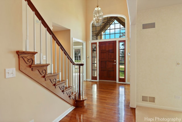 entryway featuring visible vents, baseboards, a high ceiling, stairway, and wood finished floors