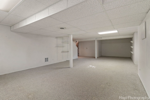 finished basement with visible vents, baseboards, a paneled ceiling, and carpet floors
